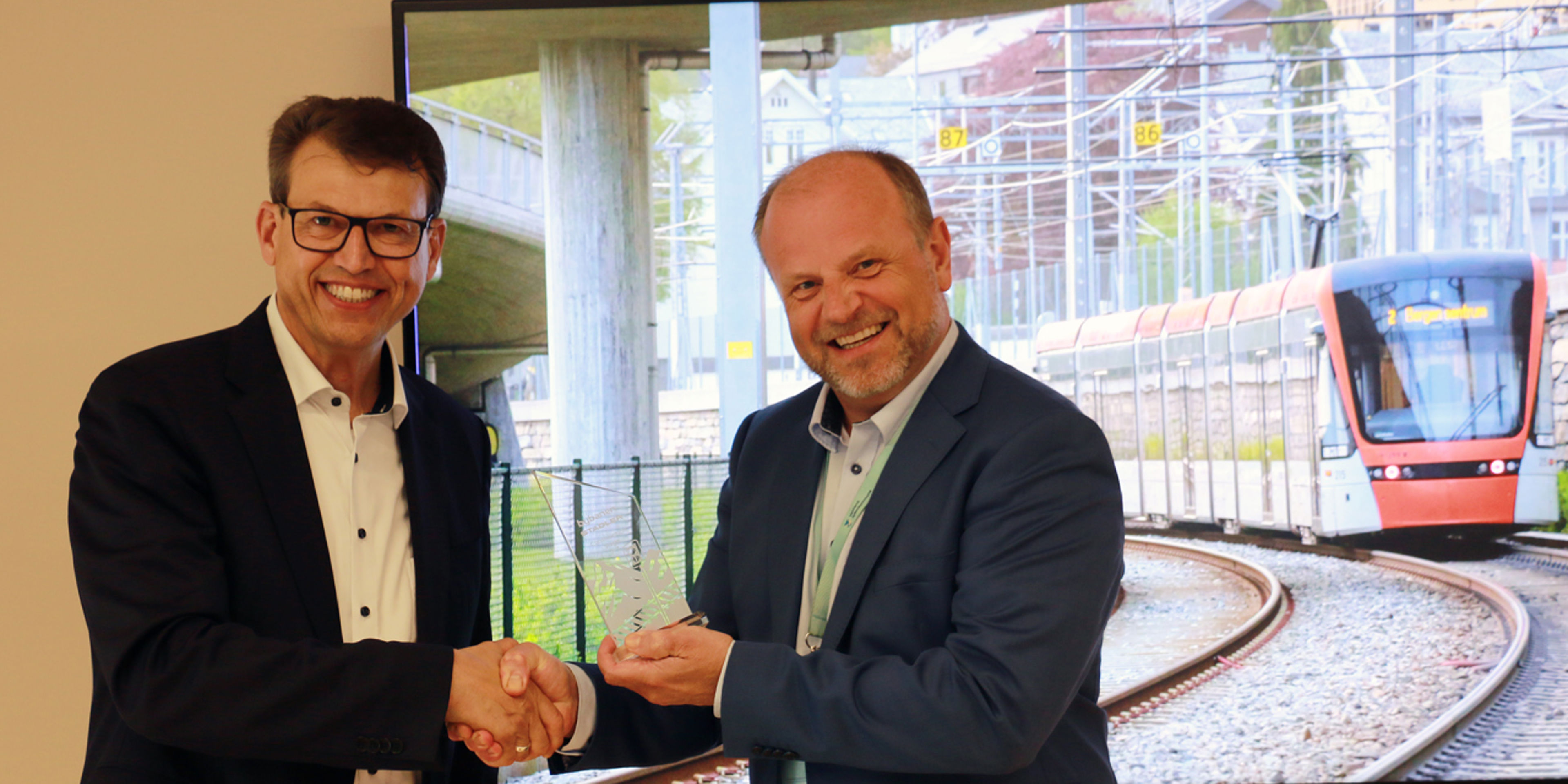 Biletet syner Managing Director Albrecht Teich i Stadler Signalling og prosjektdirektør Arve Tjønn Rinde i Bybanen Utbygging gratulerar kvarandre under kontraktsigneringa i Bergen 22. april. 