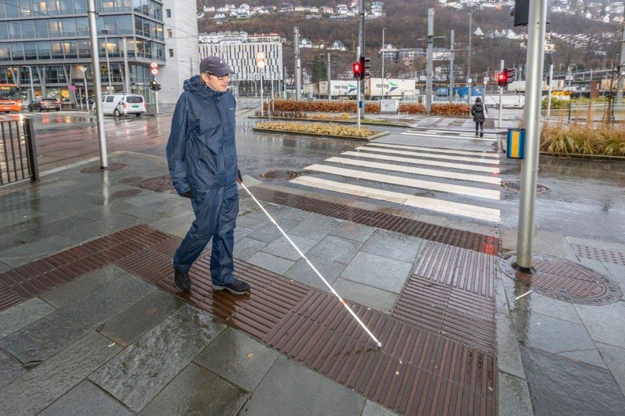 BIletet syner ein mann som med ein stokk følg ledelinene for å kome seg meldom busshaldeplass og bybanehaldeplass