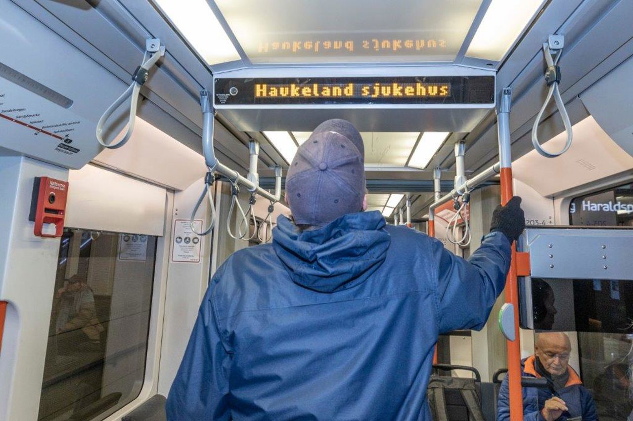 Bilete syner ein mann med redusert syn som ser på eit digitalt skilt inne i ei bybanevogn der det står Haukeland sjukehus på. Samstundes blir haldeplassen annonsert av eit spesielt musikkstykke og ei stemme som seier haldeplassnamnet.