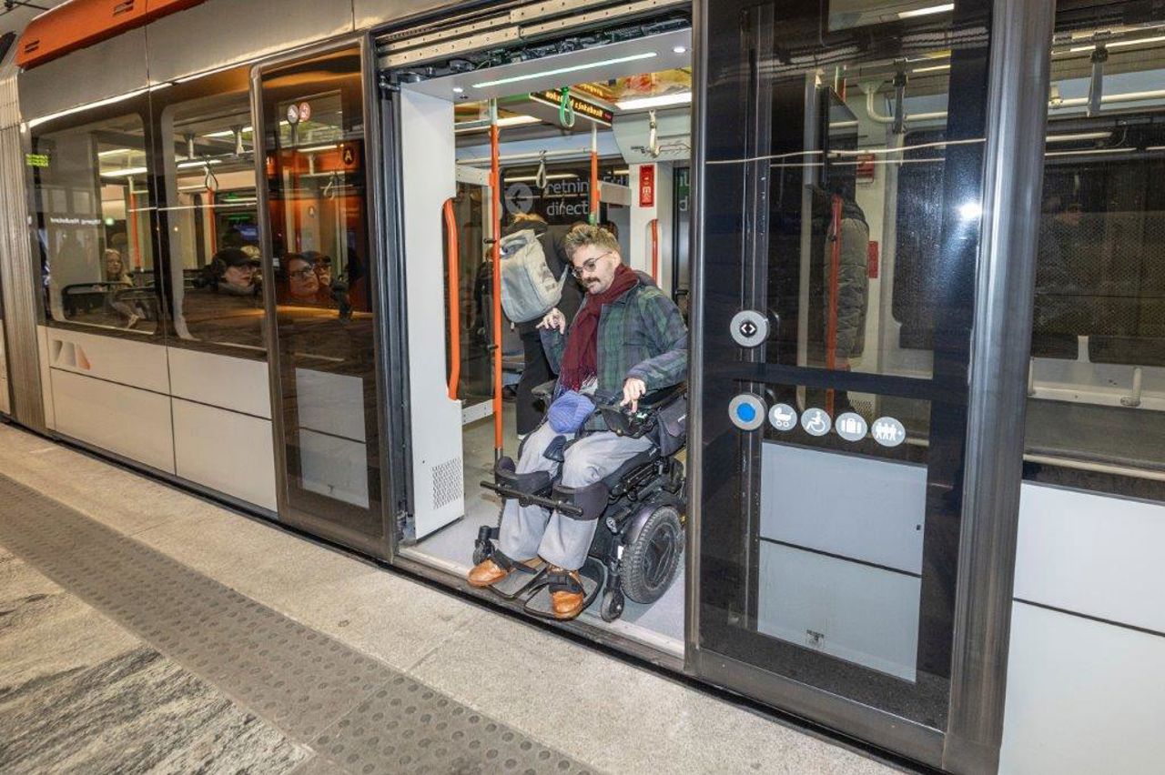 Biletet syner ein mann som køyrer enkelt køyrer ut døra på Bybanen ut på plattformen fordi vogn og plattform er på same nivå og utan glipe mellom vogn og perrong.