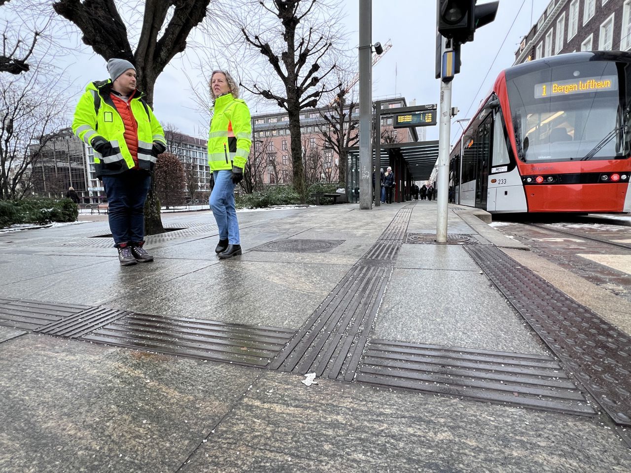 Biletet syner Petter Jacob Fredriksen, prosjektleiar ombruk i COWI og Ingrid Haukeland ved  Byparken haldeplass i Bergen sentrum. I forgrunnen ledelinjer for blinde og svaksyne som skal gjenbrukast andre plassar når haldeplassen forsvinn.