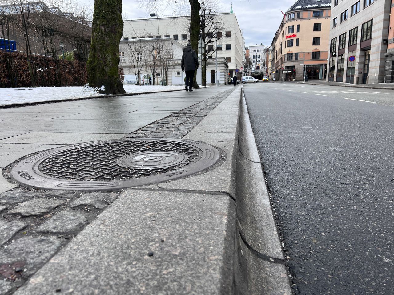 Biletet er eit nærbilete av fortauskanten ved bussholdeplassen i Christiesgate. Kantsteinen har eit bua design ned mot vegen.